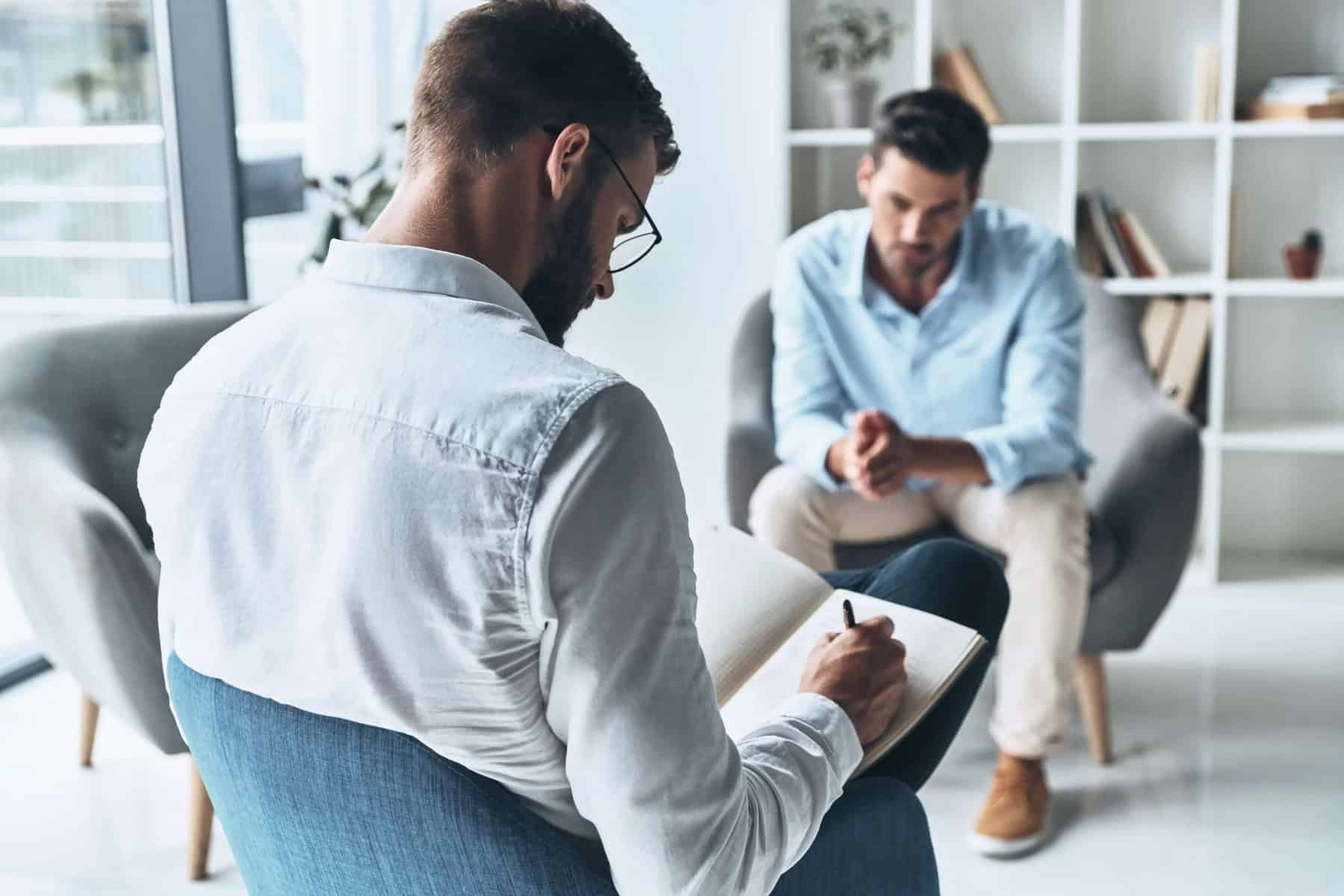 Young frustrated man solving his mental problems while having therapy session with psychologist
