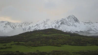 snow-capped Wasatch Mountains above green foothills in Ogden Valley, Utah.